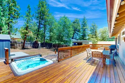 a hot tub on a deck with a table and chairs at Lazy Bear Cabin ~ Dog-friendly home with private hot tub, ping-pong, basketball & firepit in Big Bear Lake