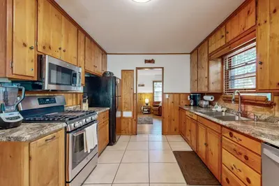 a kitchen with wooden cabinets and a stove top oven at Quiet Cabin ~ End of Cul-De-Sac Location Private Hot Tub, Fenced Yard, Boat Parking in Big Bear Lake