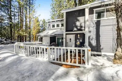 a house with a white fence in the snow at Moose-in' Around ~ Walk to Slopes Mountain Home with Private Hot Tub, Ski Locker & Playground in Big Bear Lake