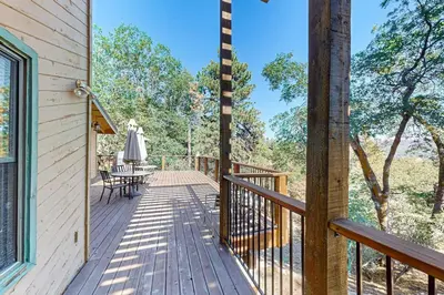 a wooden deck with a table and chairs on it at Big Bear 7th Heaven ~ Lakeview Chalet with Hot Tub, Sauna, Grill, Great Deck Views in Fawnskin