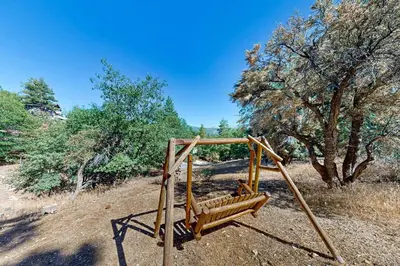 a wooden swing set on a hill with trees at Big Bear 7th Heaven ~ Lakeview Chalet with Hot Tub, Sauna, Grill, Great Deck Views in Fawnskin