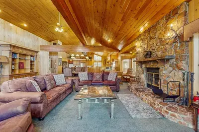 a living room with couches and a stone fireplace at Big Bear 7th Heaven ~ Lakeview Chalet with Hot Tub, Sauna, Grill, Great Deck Views in Fawnskin