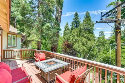 a porch with rocking chairs and a table and a view of trees at Forest Views and Fire Pit! Cozy Cabin in Crestline in Crestline