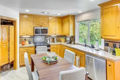 a kitchen with wooden cabinets and a wooden table at Forest Views and Fire Pit! Cozy Cabin in Crestline in Crestline