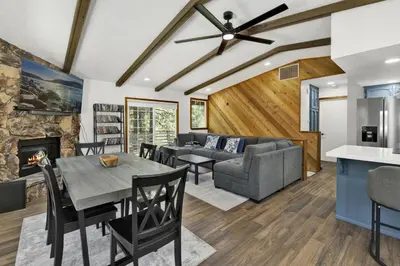 a living room with a table and a couch at The Fox Den Big Bear ~ Modern Mountain View Retreat w/ Hot Tub in Big Bear City