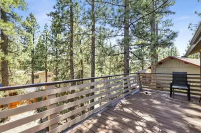 a bench on the deck of a house at The Fox Den Big Bear ~ Modern Mountain View Retreat w/ Hot Tub in Big Bear City