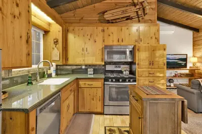 a kitchen with wooden cabinets and a stove top oven at Orchard Family Cabin Near Historic Big Bear Village Walk to Marina in Big Bear Lake