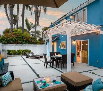 a patio with a blue house with a pergola at Sea La Vie by Paradise Retreats in Ventura