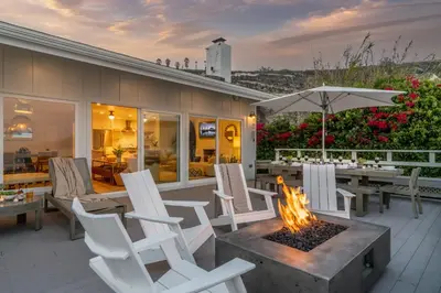 a patio with white chairs and a fire pit at The Cove at Rincon by Paradise Retreats in Carpinteria