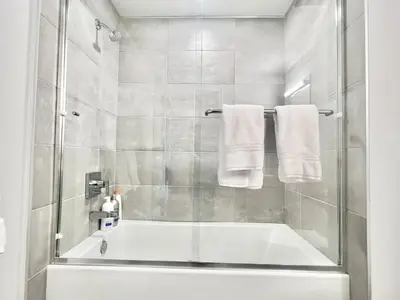 a bathroom with a tub and a shower with towels at Silver Lake 1 Bedroom Condo Suite with Balcony and Parking in Los Angeles