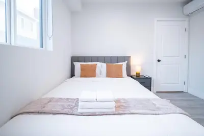 a bedroom with a large white bed with orange pillows at Modern 2BR2BA Home Near USC Walk to Campus in Los Angeles