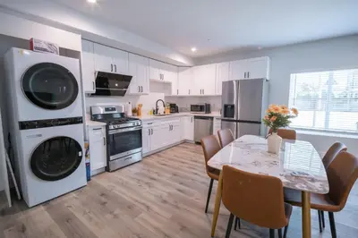 a kitchen with white cabinets and a table with chairs at Modern 2BR2BA Home Near USC Walk to Campus in Los Angeles