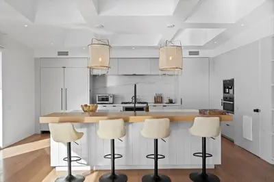 a kitchen with white cabinets and a counter with stools at Surfside Malibu by Stay Awhile Villas in Malibu
