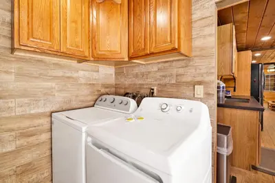 a washer and dryer in a kitchen with wooden cabinets at Lily's Bear Cabin #2544 in Big Bear Lake