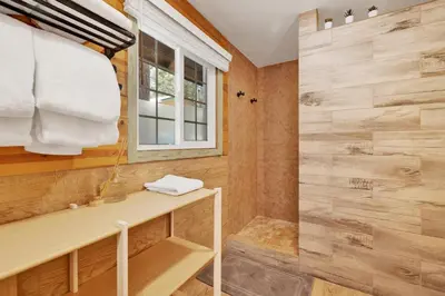 a bathroom with a shower with wooden walls and a window at Lily's Bear Cabin #2544 in Big Bear Lake