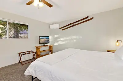 a white bedroom with a bed and a television at Orchard Family Cabin #2560 in Big Bear Lake