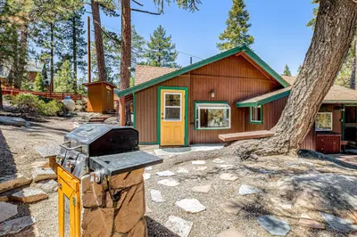 a house with a stove in front of a tree at Castle Rock Cabin #178 in Big Bear Lake