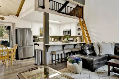 a living room with a couch and a kitchen at Moose-in' Around in Big Bear Lake