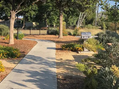 a walkway in a park with a bench and trees at Magic Splash Getaway in Santa Clarita