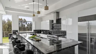 a kitchen with a large island with black chairs at Luxe 8000 sqft w 2 Pools Sauna Putting Green Game Room Alta Vista Estate in Los Angeles
