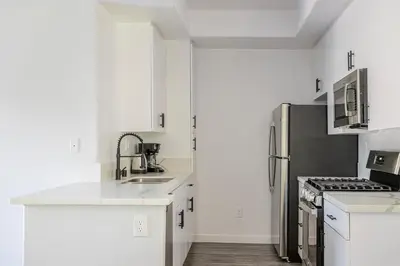 a kitchen with white cabinets and a stainless steel refrigerator at Blueground Sawtelle view nr Westwood Park LAX-1396 in Los Angeles