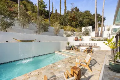 a patio with a swimming pool with chairs and a table at Villa Avra by Stay Awhile Villas in Los Angeles