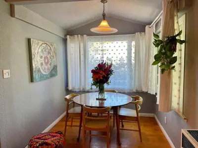 a dining room table with a vase of flowers on it at Cozy Beach Bungalow- Happynest in Long Beach