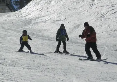 a group of three people skiing down a snow covered slope at Getaways at Lagonita Lodge in Big Bear Lake