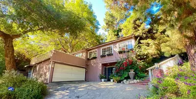 a house with a garage and a tree at Hollywood Hills Spa Retreat Oasis with Tree Top Views, Private Jacuzzi Style Tub, Steam Room, Magical Half Acre Acre Garden and Patio, Free Parking for 2 cars, in LA's most Serene, Central Desirable Area in Los Angeles