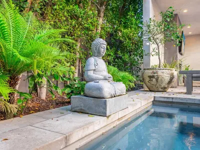 a statue sitting next to a pool in a garden at Sycamore Villa in Los Angeles
