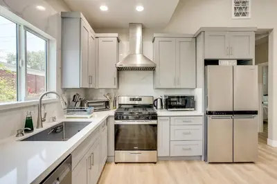 a kitchen with white cabinets and stainless steel appliances at 2 Mi to Disneyland Home with Furnished Patio! in Anaheim
