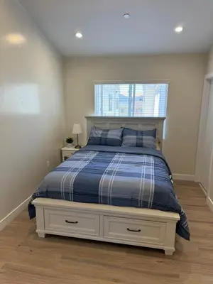 a bedroom with a bed with a blue comforter and a window at cozy & Elegant Torrance Apartment with balcony in Torrance