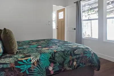 a bedroom with a bed with a colorful comforter and a window at All New Apt Mins Beach, Downtown & Convention Ctr LB ADU in Long Beach