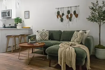 a living room with a green couch and a table at All New Apt Mins Beach, Downtown & Convention Ctr LB ADU in Long Beach