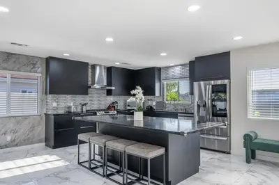 a kitchen with black cabinets and a large island with bar stools at Bellaire in Garnsey