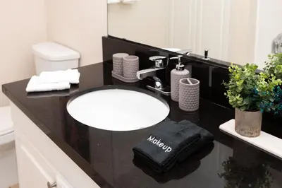 a bathroom with a white sink and a black counter at Ocean 2min, Romantic Bath, Cinema, Pool, Arcade in Marina del Rey