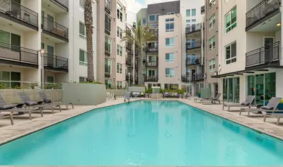 a large swimming pool with chairs and buildings at Mid Century With Pool GYM and Parking 10min to Cedars in Los Angeles