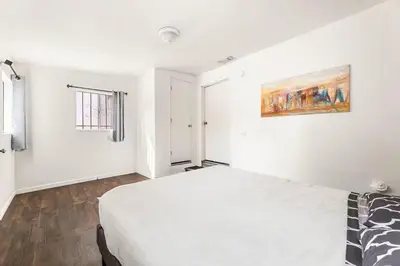 a white bedroom with a bed and a painting on the wall at Spacious 4 bedroom home by Melrose and 10 minutes to Hollywood Walk of Fame in Los Angeles