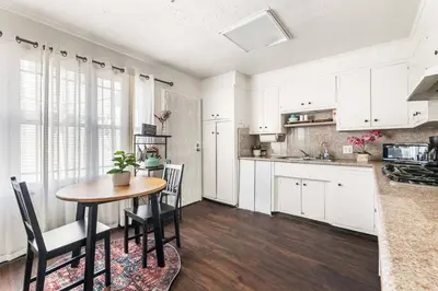 a kitchen with white cabinets and a table and chairs at Spacious 4 bedroom home by Melrose and 10 minutes to Hollywood Walk of Fame in Los Angeles