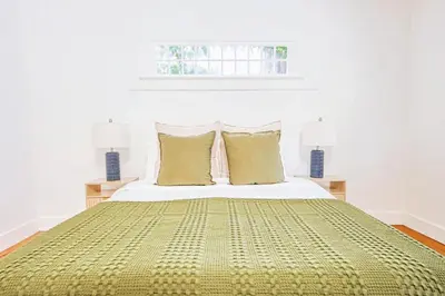 a bed with a green blanket and pillows on it at Inviting 3BR Home with Porch & Greenery in Los Angeles