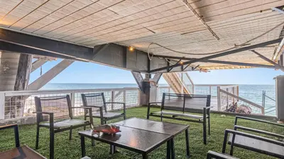 a patio with chairs and tables and a view of the ocean at Beach Retreat with Oceanfront Balconies Direct Beach Access Pacific Coast Outlook by AvantStay in Malibu Beach