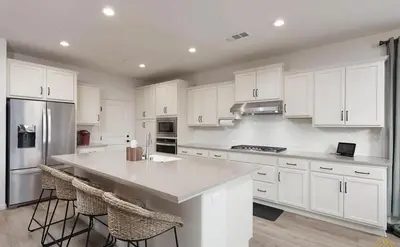 a kitchen with white cabinets and a kitchen island with stools at Modern 3BR Home Gated Community in Bakersfield