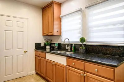 a kitchen with wooden cabinets and a sink and a window at Near LA Cozy Home with Full Kitchen & Laundry in San Gabriel