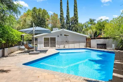 a swimming pool with an umbrella and a house at Hillside Modern Retreat with pool BBQ and MORE in Los Angeles