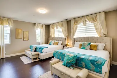 a bedroom with two beds and a couch and windows at 3 Mi to Disneyland Home with Hot Tub and Game Room in Anaheim