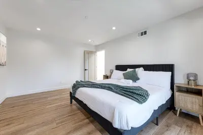 a bedroom with a large bed with white walls and wooden floors at LA Haven Spacious Townhome in Sherman Oaks Community Hospital Heliport