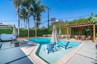 a swimming pool with two chairs and umbrellas at Modern Pool house with hot tub and relaxing backyard in Long Beach