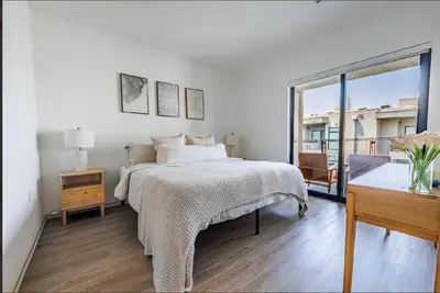 a white bedroom with a bed and a balcony at Beautiful Apartment in Hollywood in Los Angeles