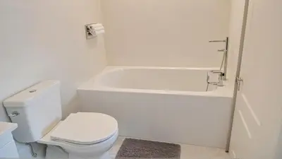 a white bathroom with a toilet and a bath tub at Modern Boutique Living in Culver City in Los Angeles