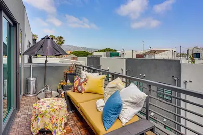 a yellow couch on a balcony with an umbrella at 2 Mi to Cabrillo Beach Luxe LA Gem with Balcony in San Pedro